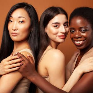 171674804-joven-mujer-bastante-asiática-caucásica-afro-posando-alegre-juntos-sobre-fondo-marrón-estilo-de